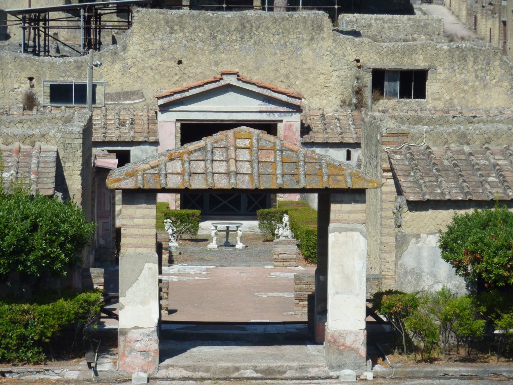 View of a villa at Herculaneum showing a courtyard with partially preserved white marble tiles on red modern base.