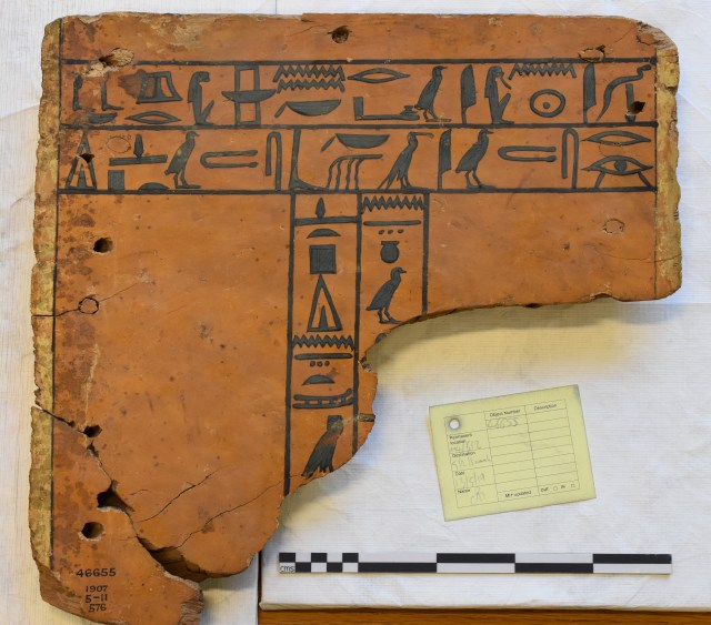 Photograph of the end panel of an ancient Egyptian coffin with two rows of hieroglyphs across the top and two columns down the centre. the bottom right corner is largely lost