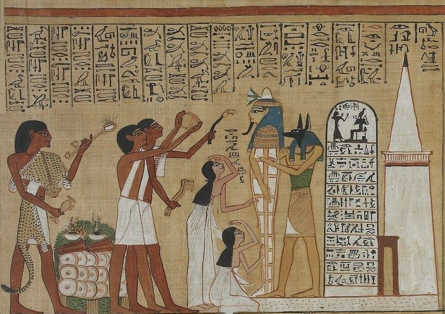 Image of an ancient Egyptian funerary papyrus with hieroglyphs at the top and a vignette below. The vignette shows a sah stood upright in its coffin before a stela and tomb with a pyramid top. Women mourn in front of the sah and men dressed as priests perform the opening of the mouth ritual and present offerings.