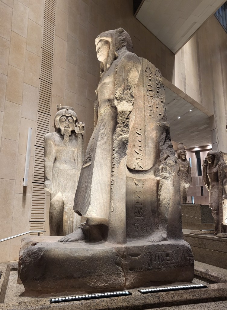 Photo of a group of Pharaonic statues of standard bearers on the Grand Staircase of the Grand Egyptian Museum.