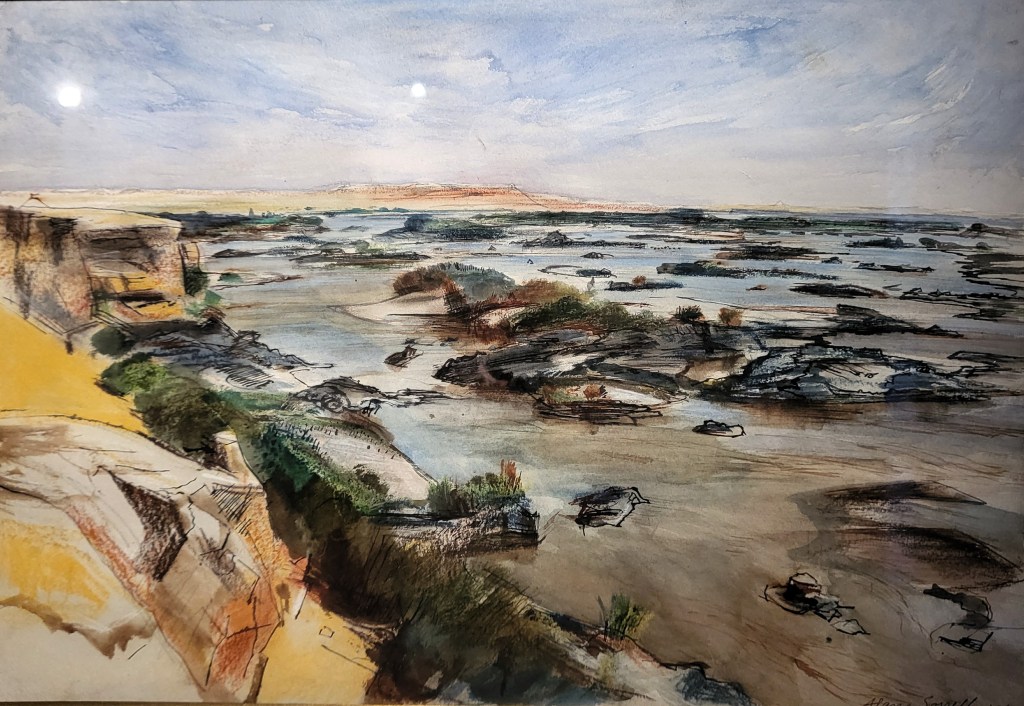 Landscape painting of a desert cliff in the left foreground with the centre right of the image occupied by the Nile, interspersed with small rocky islands. The left background shows a yellow desert, with low hills.