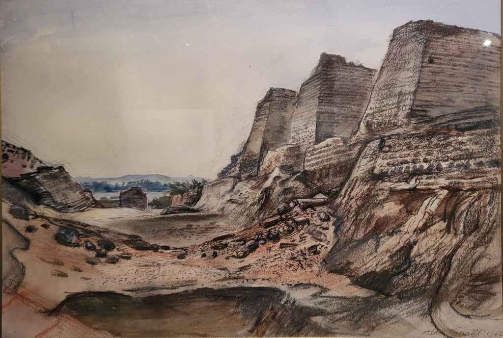 Painting of the large mudbrick towers and walls of the ancient Egyptian fort of Buhen, taken from the deep perimeter ditch, emphasising the scale of the fortification. The Nile and desert hills are visible in the background.
